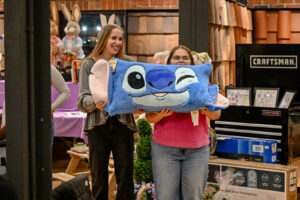 New Lexington High School Live Auction assistants holding a special pillow item.
