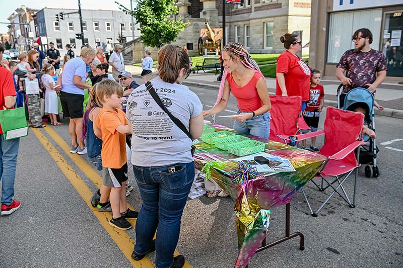 Children choosing giveaway prizes at The Beauty Hut table on Main Street in New Lexington during the 2026 Chalk It Up to Summer event for kids and families.