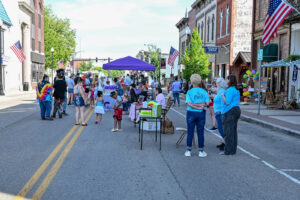 Tents and tables line Main Street in New Lexington during the 2026 Chalk It Up to Summer event for kids and families.