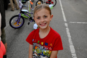 Child smiling on Main Street in New Lexington during the 2026 Chalk It Up to Summer event for kids and families.