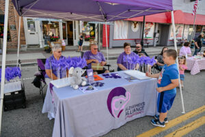 The Alzheimer's Alliance manning their booth on Main Street in New Lexington during the 2026 Chalk It Up to Summer event for kids and families.