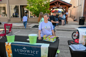 Volunteer handing out bubbles at the Ludowici table on Main Street in New Lexington during the 2026 Chalk It Up to Summer event for kids and families.