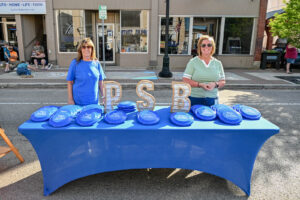 The Peoples State Bank table with free frisbees on Main Street in New Lexington during the 2026 Chalk It Up to Summer event for kids and families.