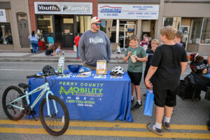 The Perry County Mobility table with bike riding information on Main Street in New Lexington during the 2026 Chalk It Up to Summer event for kids and families.