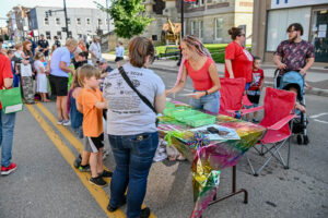 Children choosing giveaway prizes at The Beauty Hut table on Main Street in New Lexington during the 2026 Chalk It Up to Summer event for kids and families.