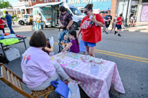 Family visiting the Happy Cones table on Main Street in New Lexington during the 2026 Chalk It Up to Summer event for kids and families.