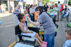 Child getting her face painted on Main Street in New Lexington during the 2026 Chalk It Up to Summer event for kids and families.