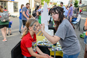 Child getting face painted on Main Street in New Lexington during the 2026 Chalk It Up to Summer event for kids and families.