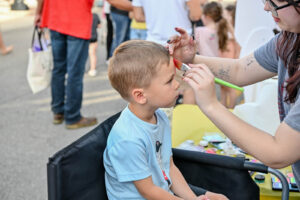 Boy getting his face painted on Main Street in New Lexington during the 2026 Chalk It Up to Summer event for kids and families.