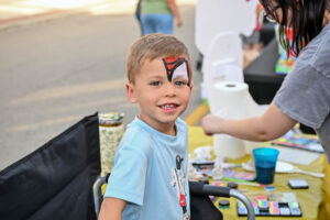 Face-painted boy smiles on Main Street in New Lexington during the 2026 Chalk It Up to Summer event for kids and families.