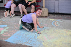 Child working on her sidewalk chalk painting on Main Street in New Lexington during the 2026 Chalk It Up to Summer event for kids and families.