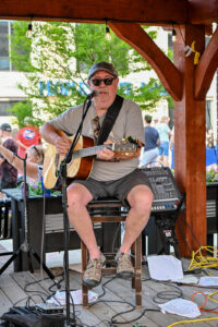 Guitarist Mike Boley singing and playing outside Trotter's on Main Street in New Lexington during the 2026 Chalk It Up to Summer event for kids and families.