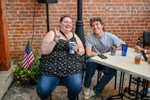 People smiling at table outside Trotter's on Main Street in New Lexington during the 2026 Chalk It Up to Summer event for kids and families.