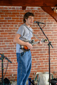 Guitarist Elliot Boley playing and singing on patio at Trotter's on Main Street in New Lexington during the 2026 Chalk It Up to Summer event for kids and families.